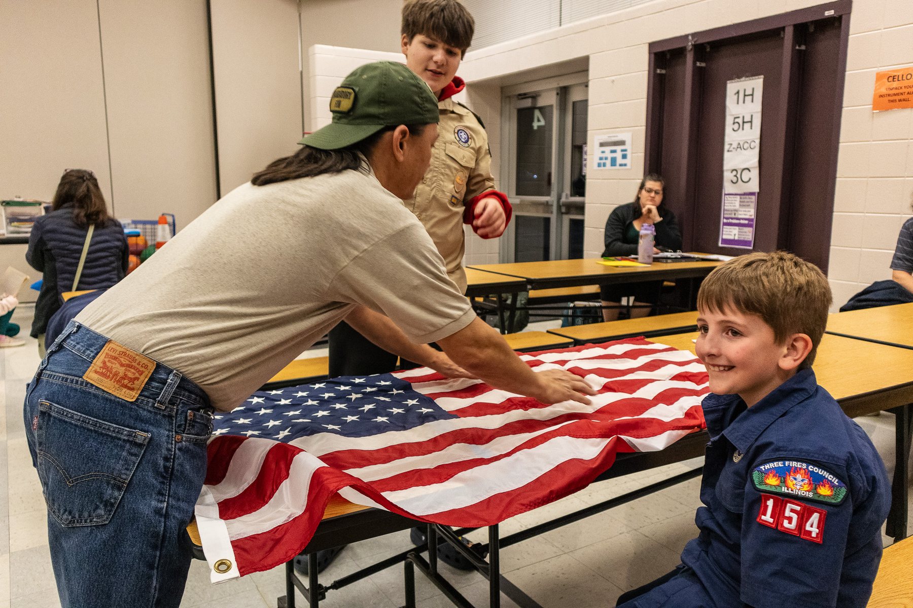 A smiling Pack 154 Scout helping fold the American flag