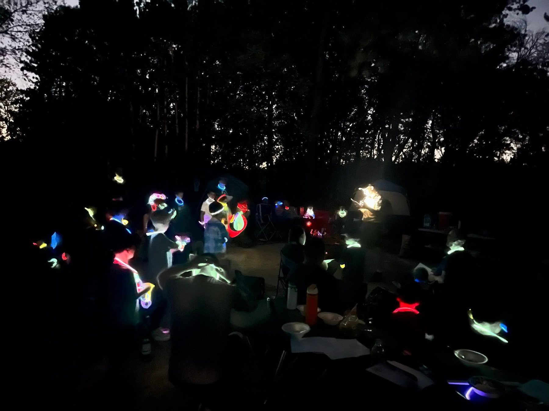 Families enjoying a glow-stick activity after dark at camp