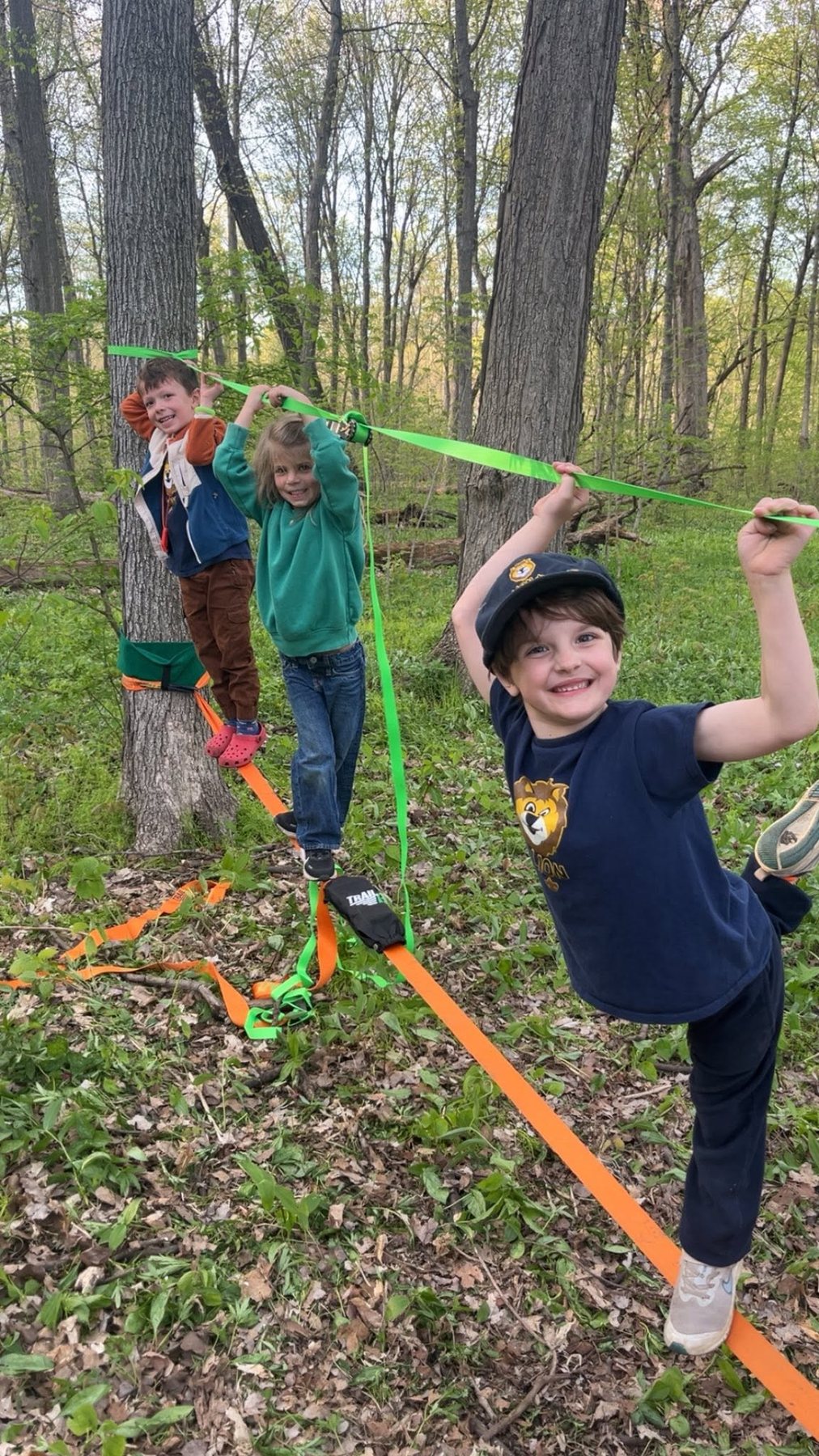 Pack 154 children smiling while trying a slackline in the woods